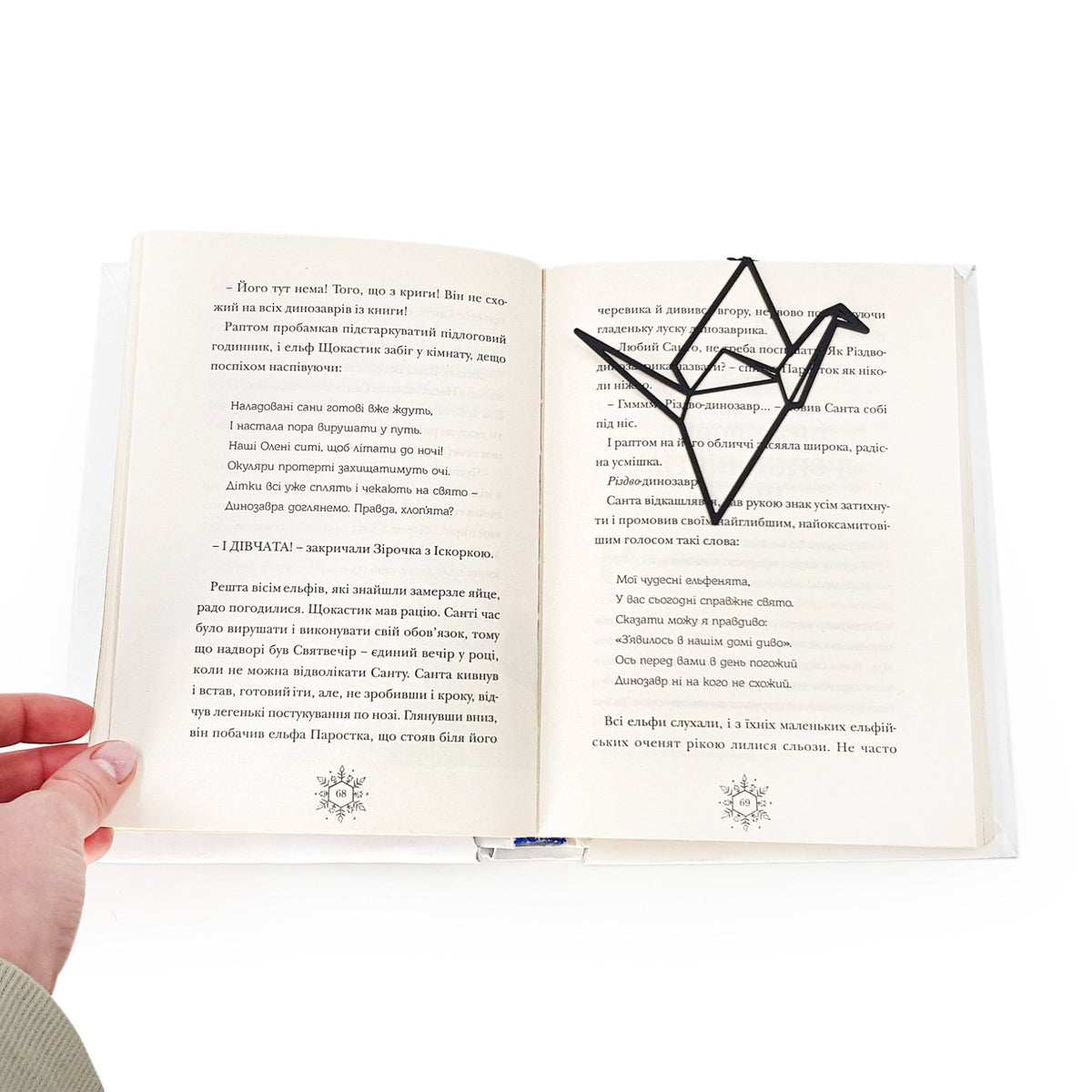 Origami Crane metal bookmark lying across the pages of an open book