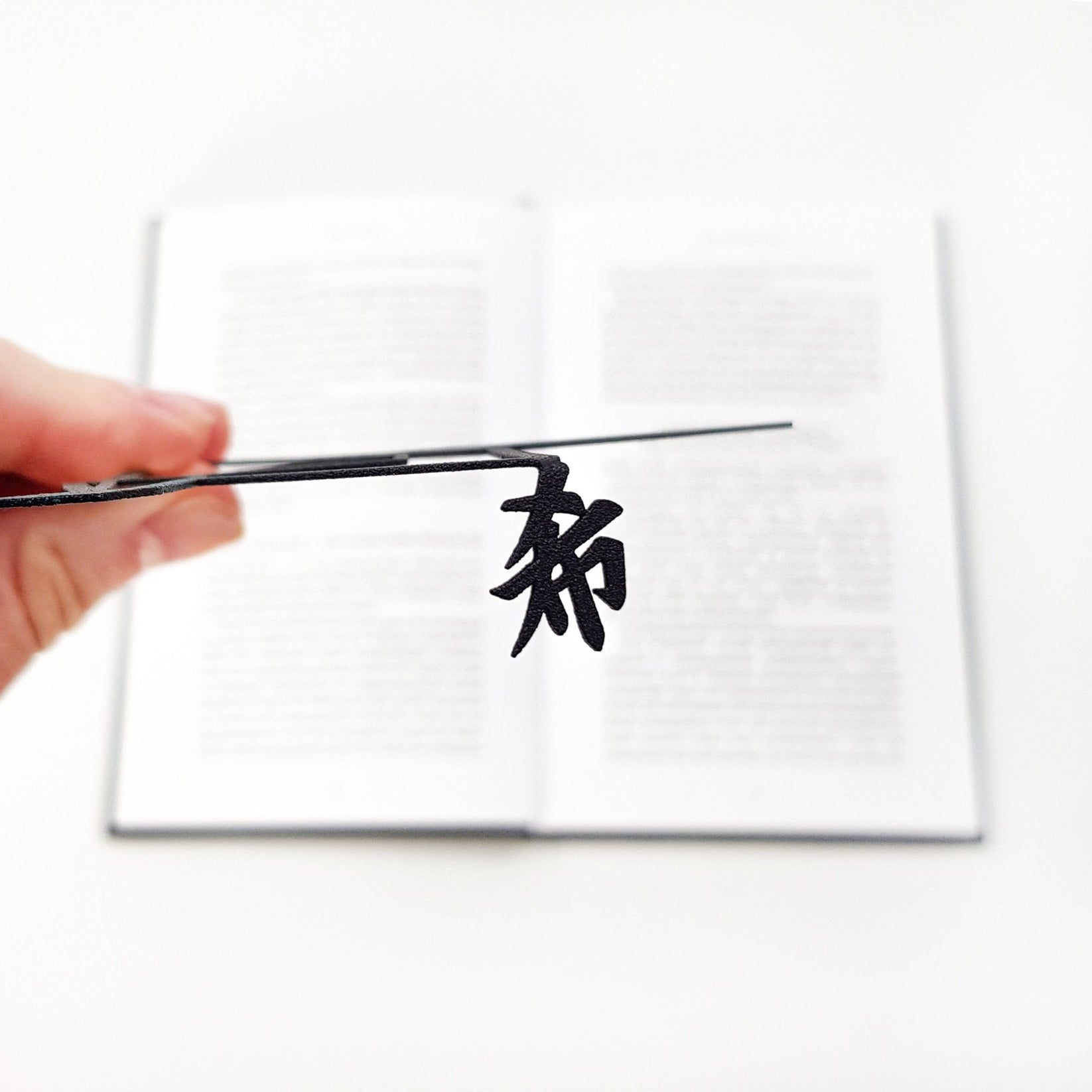 Origami Crane metal bookmark held up beside an open book