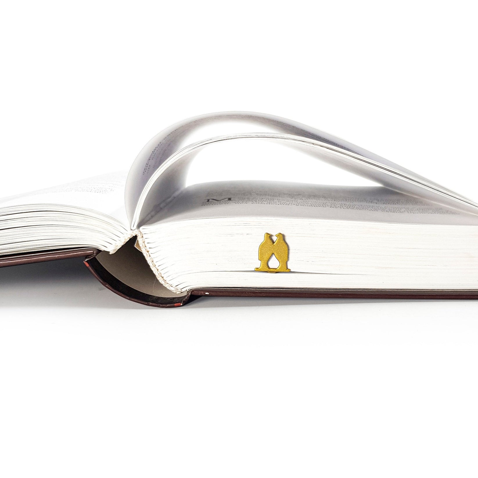 Pair of Pigeons metal bookmark in gold in a closed book, only its top showing above the pages