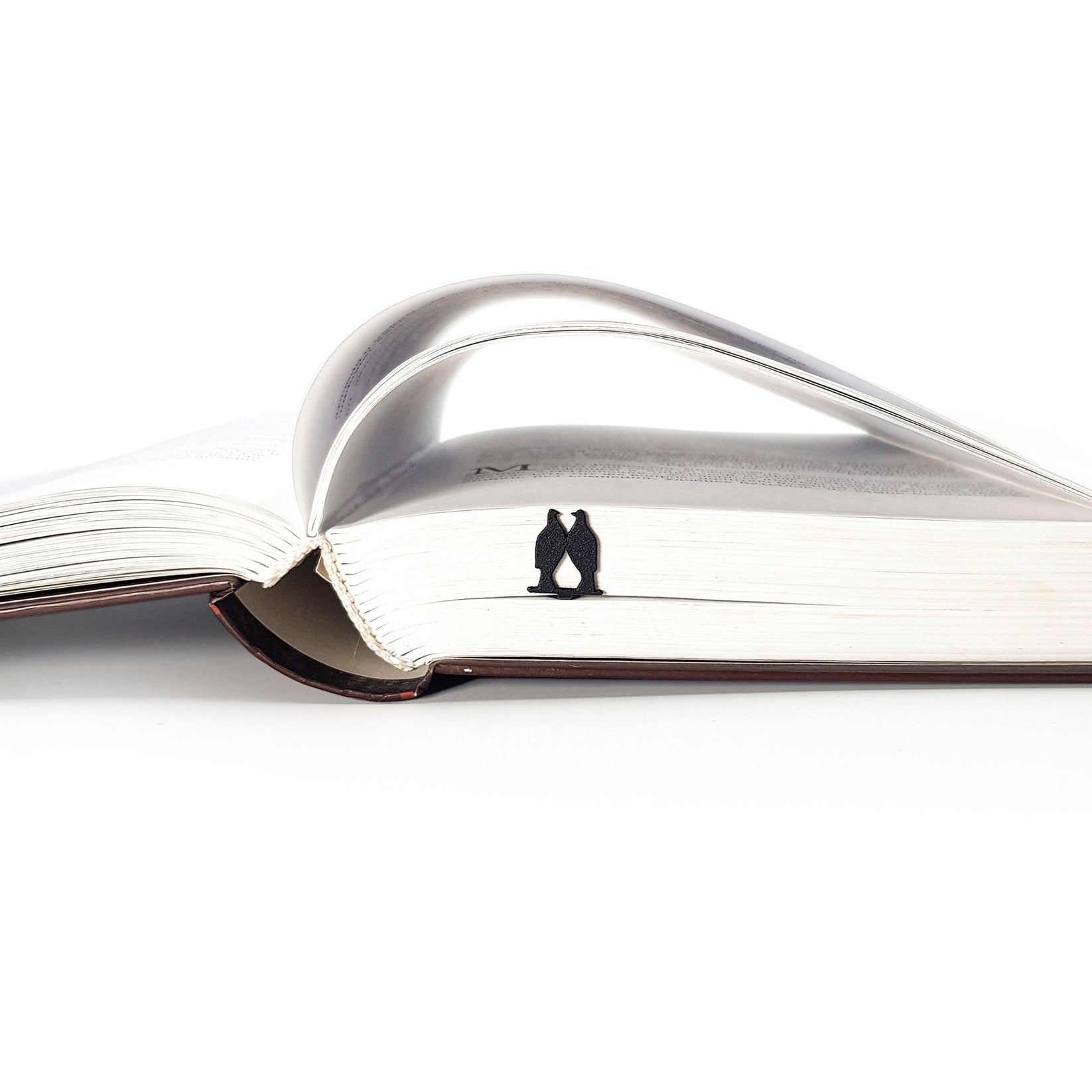 Pair of Pigeons metal bookmark seen from the edge of a closed book