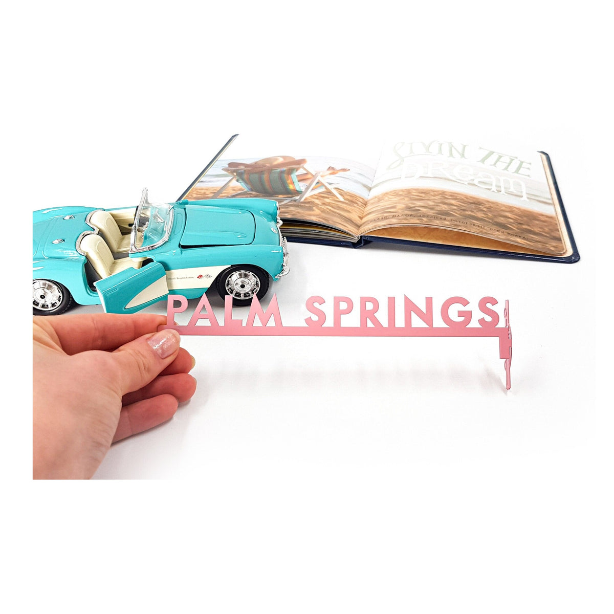 Palm Springs metal bookmark in red held in a hand above an open book