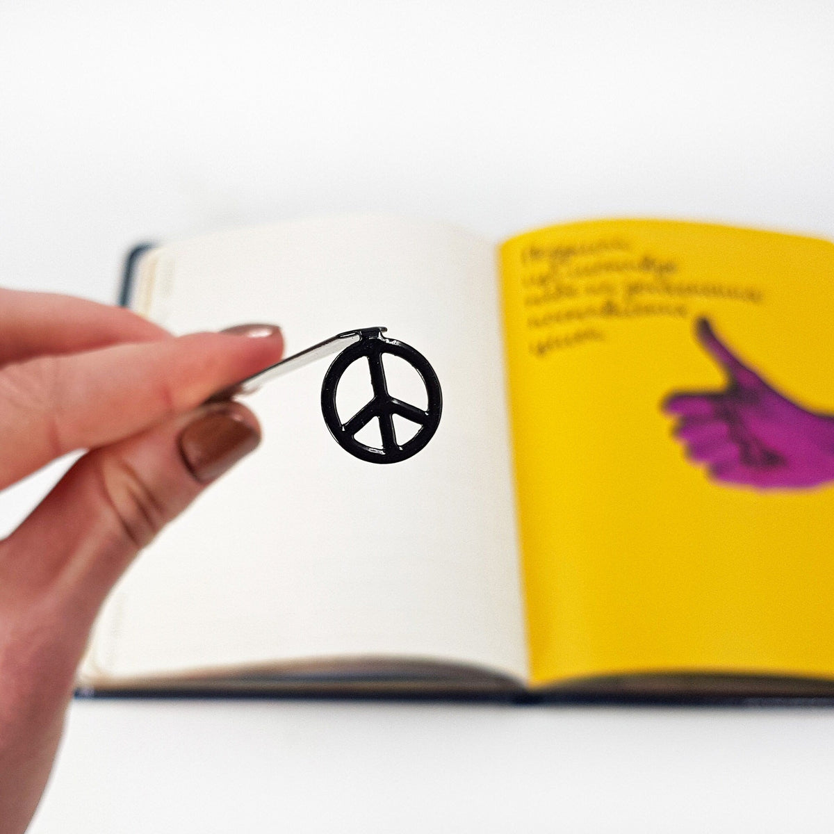 Peace metal bookmark held in a hand above an open book