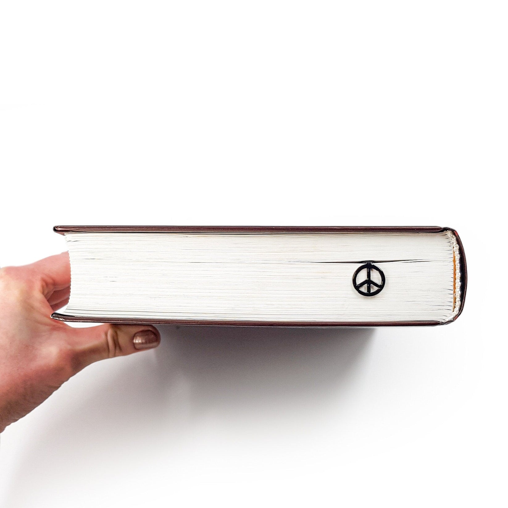 Peace metal bookmark held up beside an open book