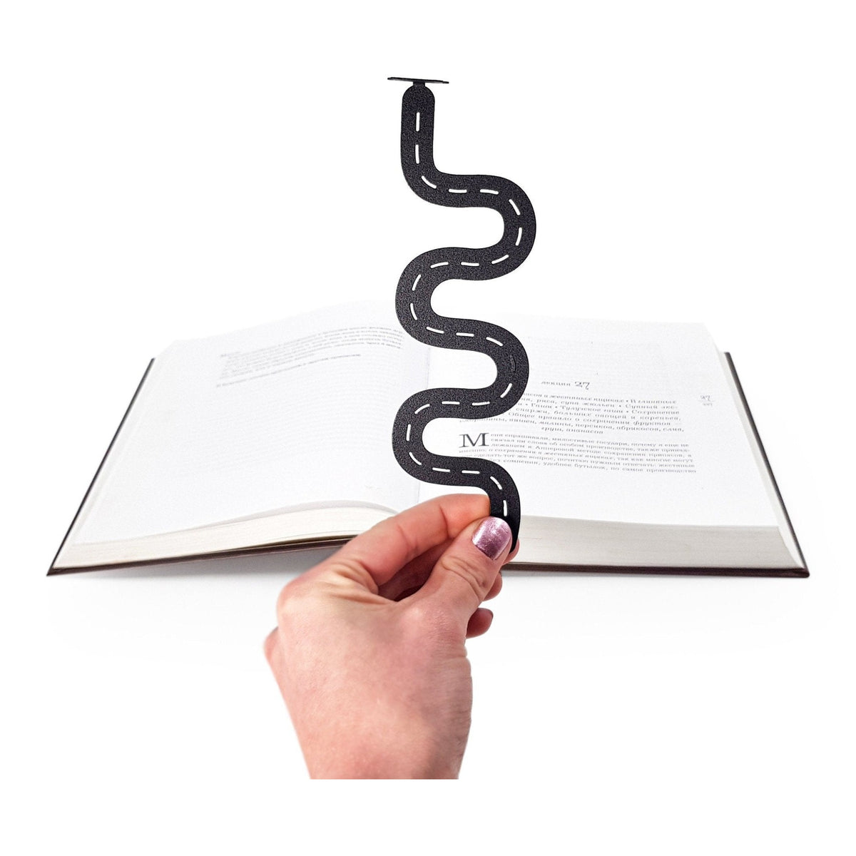 Peace Trip metal bookmark held in a hand above an open book