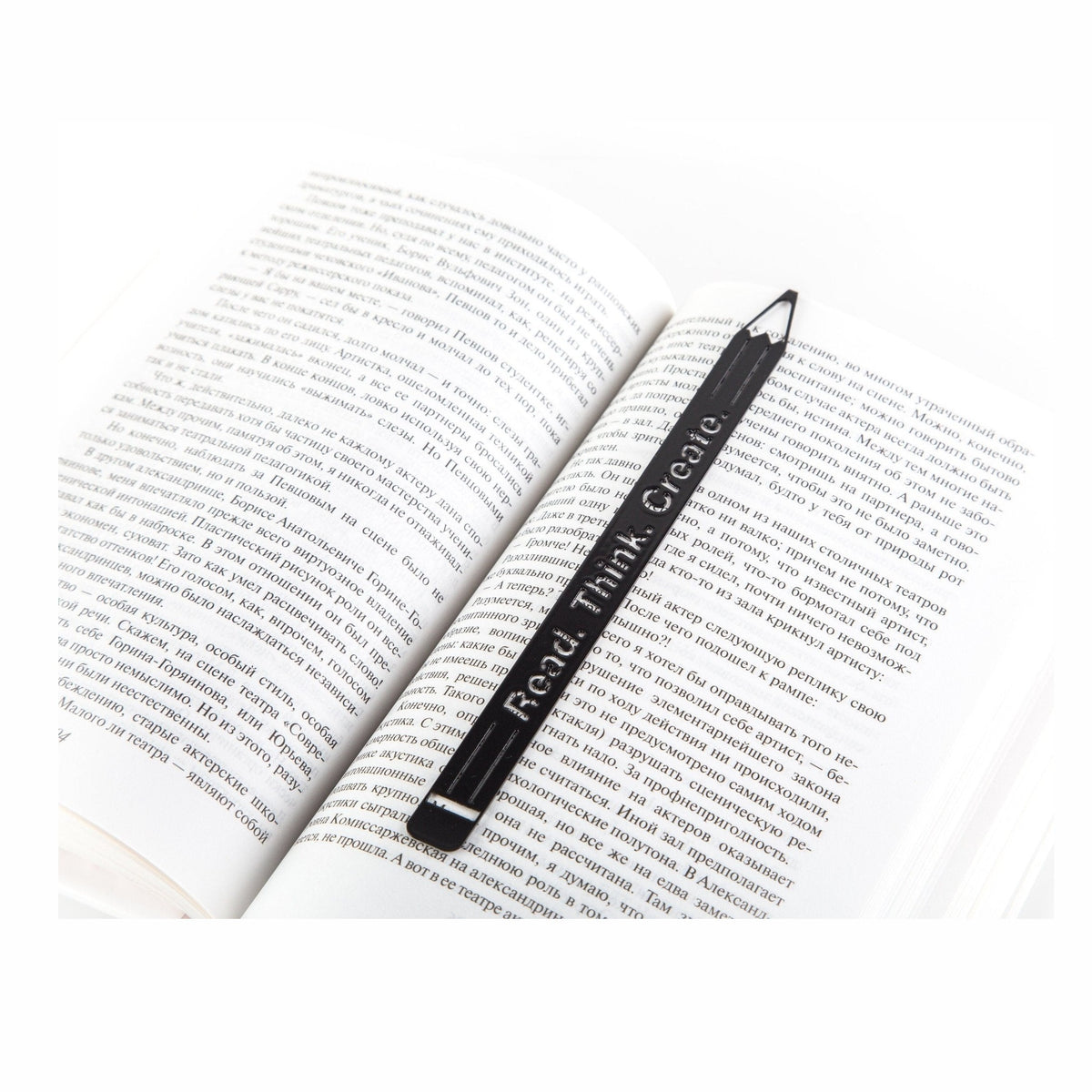 Pencil Read, Think, Create metal bookmark resting on the pages of an open book