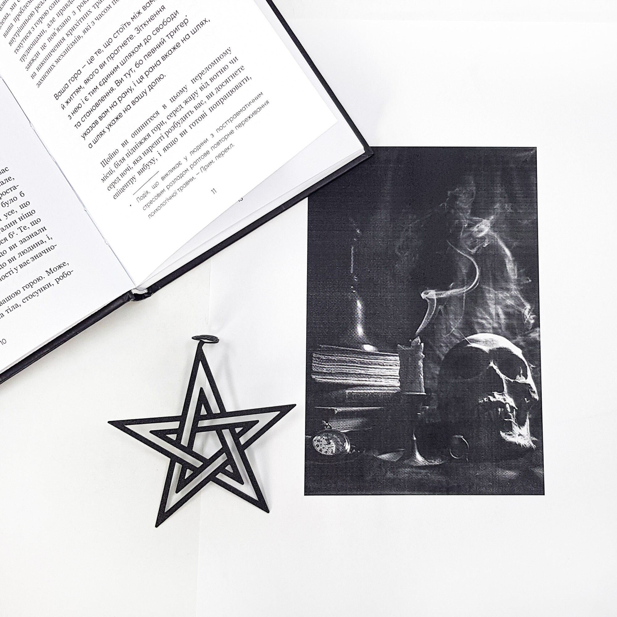 Open book with a black and white illustration of a person in a lab coat and a pentagram bookmark on a white surface.