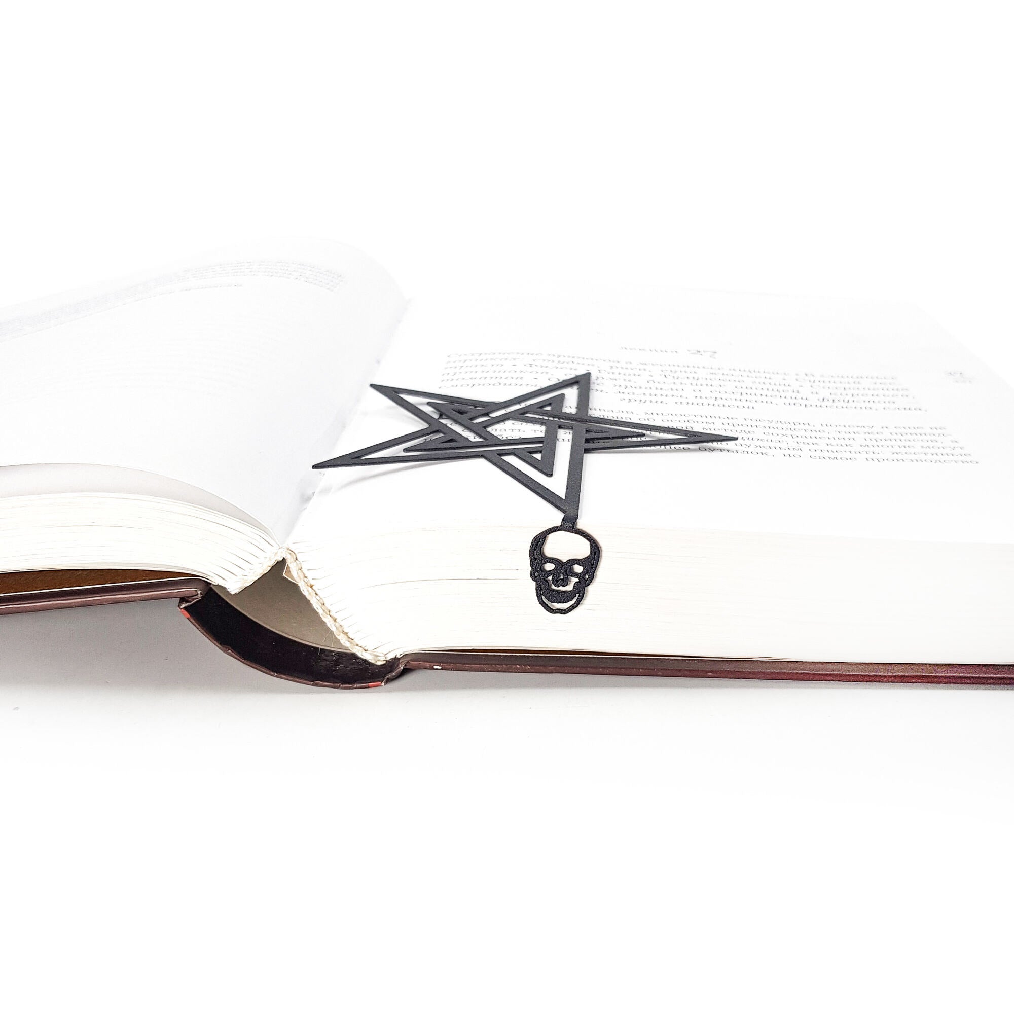 Open book with a pentagram and skull bookmark on a white background