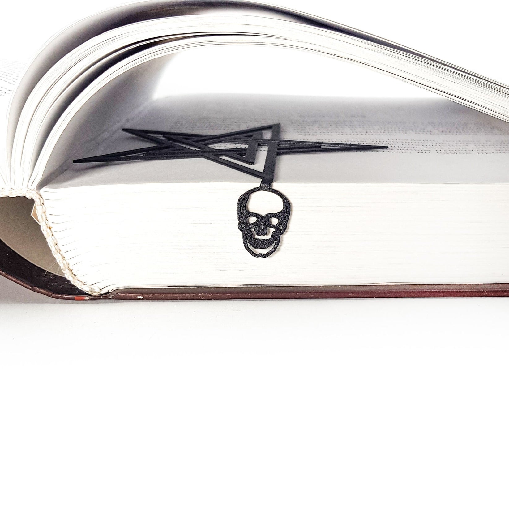 Pentagram & Skull metal bookmark in a closed book, only its top showing above the pages