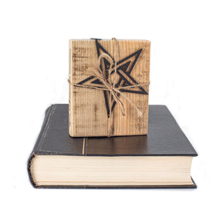 Gift-wrapped black metal pentagram bookmark tied with jute string and placed on top of a closed vintage book — gothic handmade reading accessory.