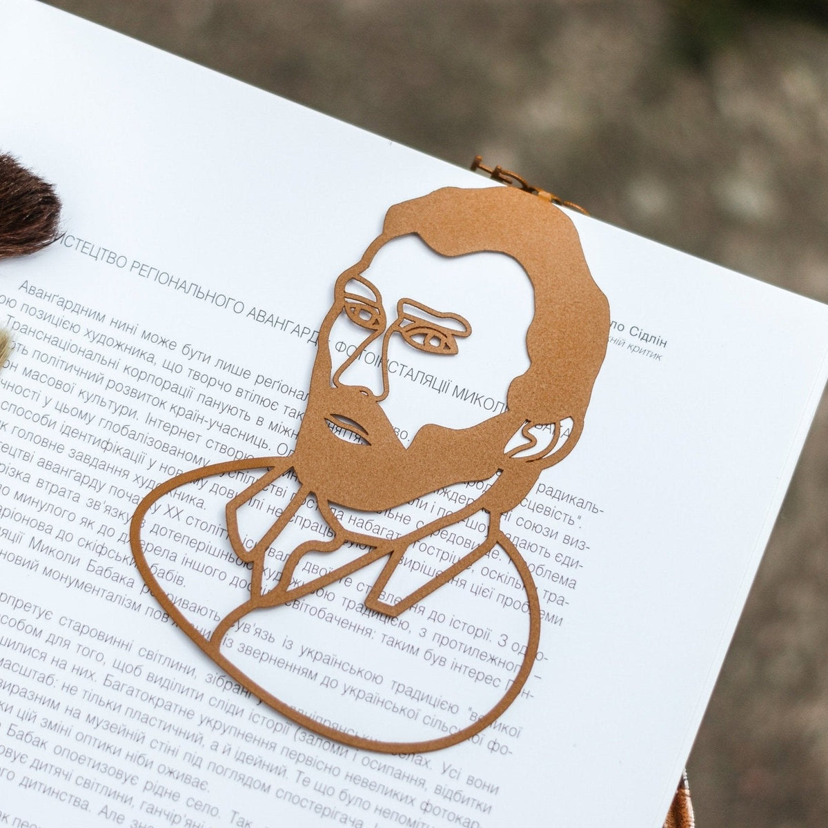 Van Gogh Portrait metal bookmark in gold resting on the pages of an open book