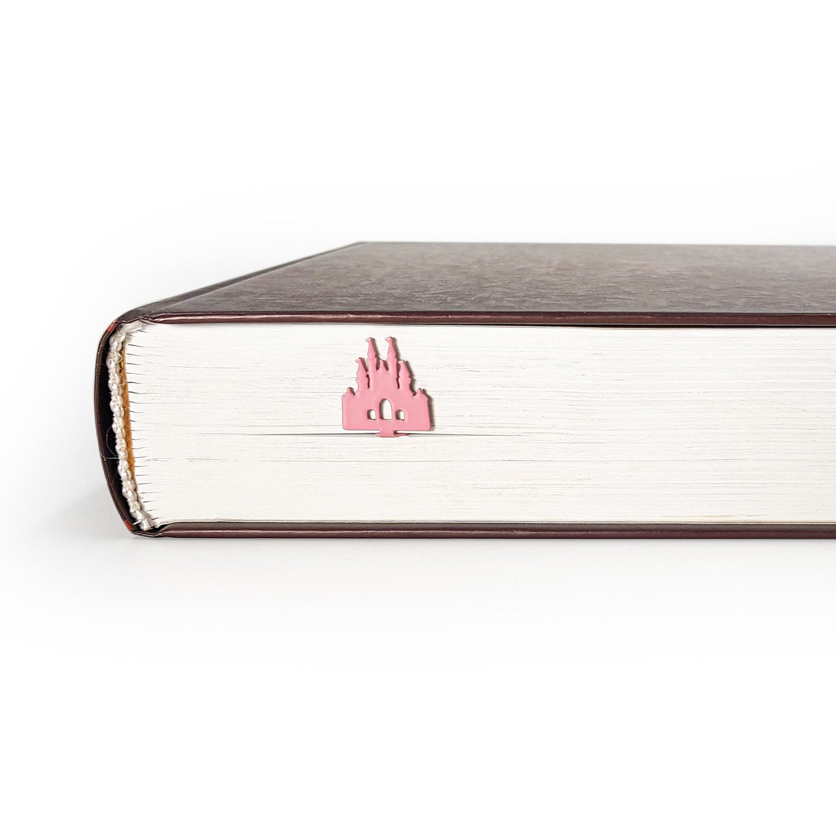 Princess Castle Pink metal bookmark in red in a closed book, only its top showing above the pages