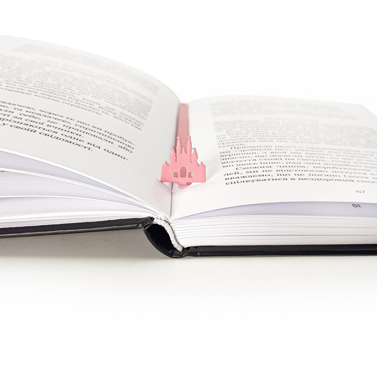 Princess Castle Pink metal bookmark in red resting on the pages of an open book