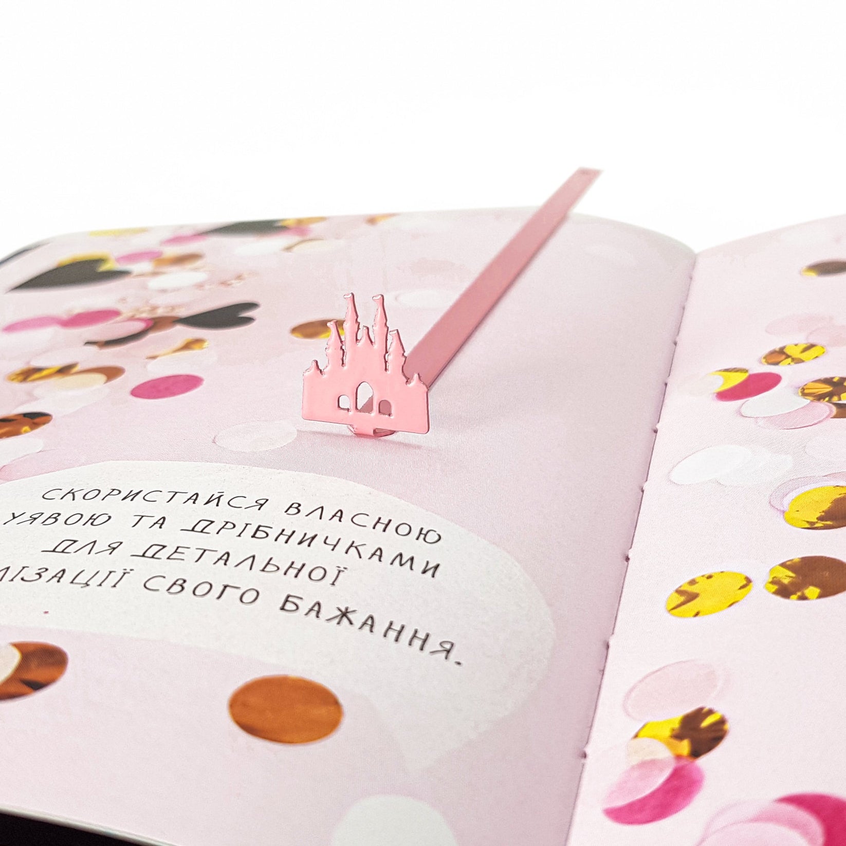 Princess Castle Pink metal bookmark in red placed on a colour illustration