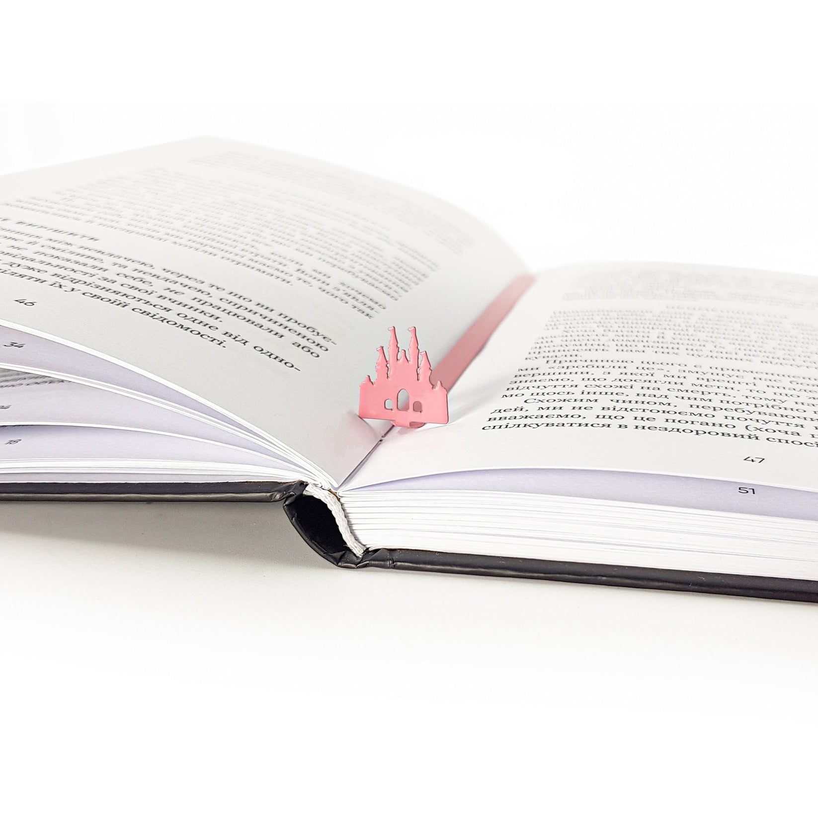 Princess Castle Pink metal bookmark in red marking a page in an open book