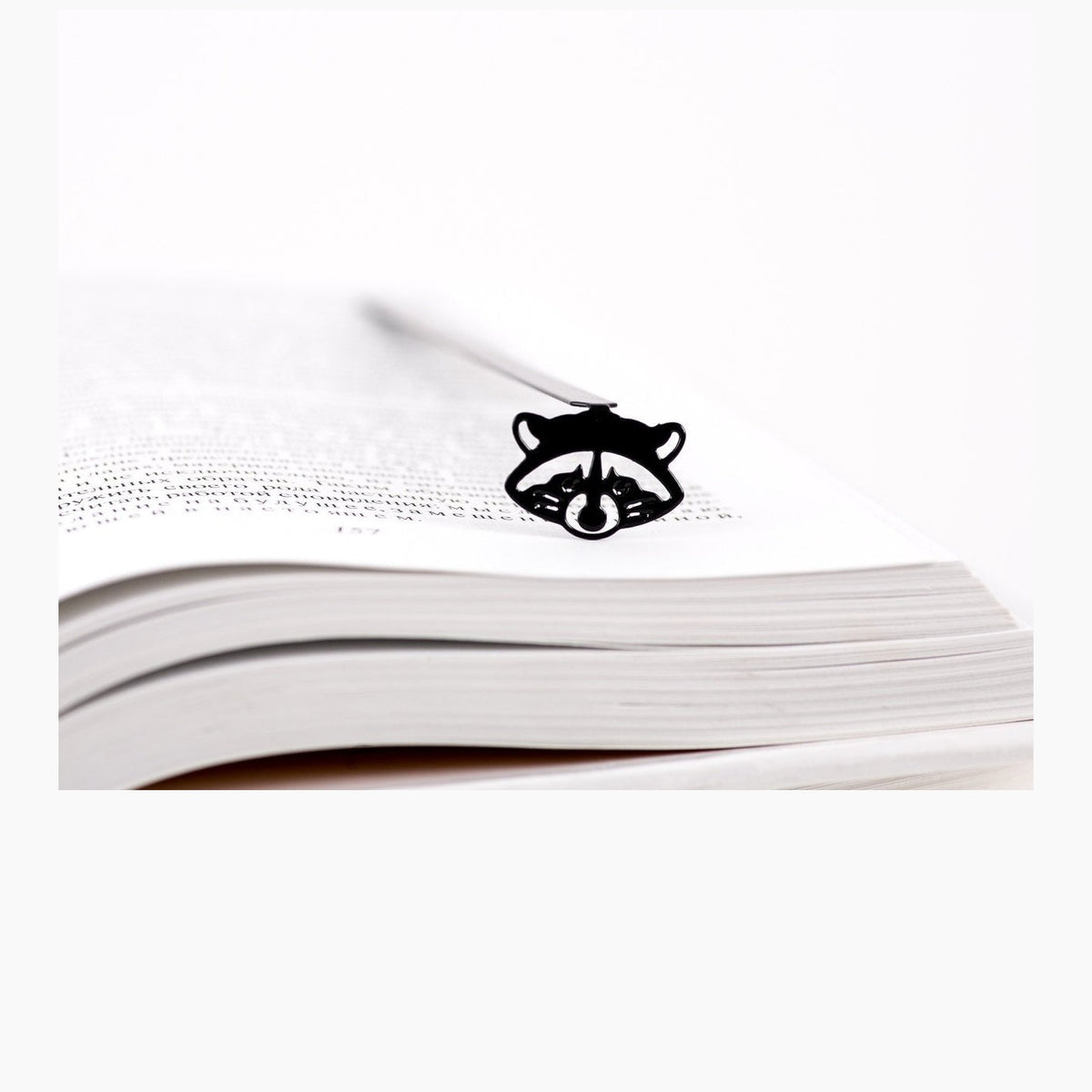 Raccoon metal bookmark resting on the pages of an open book