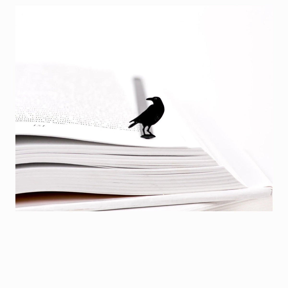 Raven metal bookmark resting on the pages of an open book