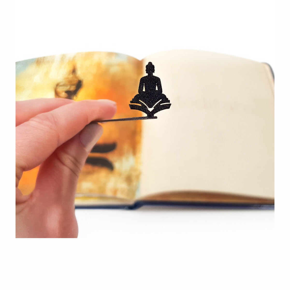 Reading Buddha metal bookmark marking a page in an illustrated book