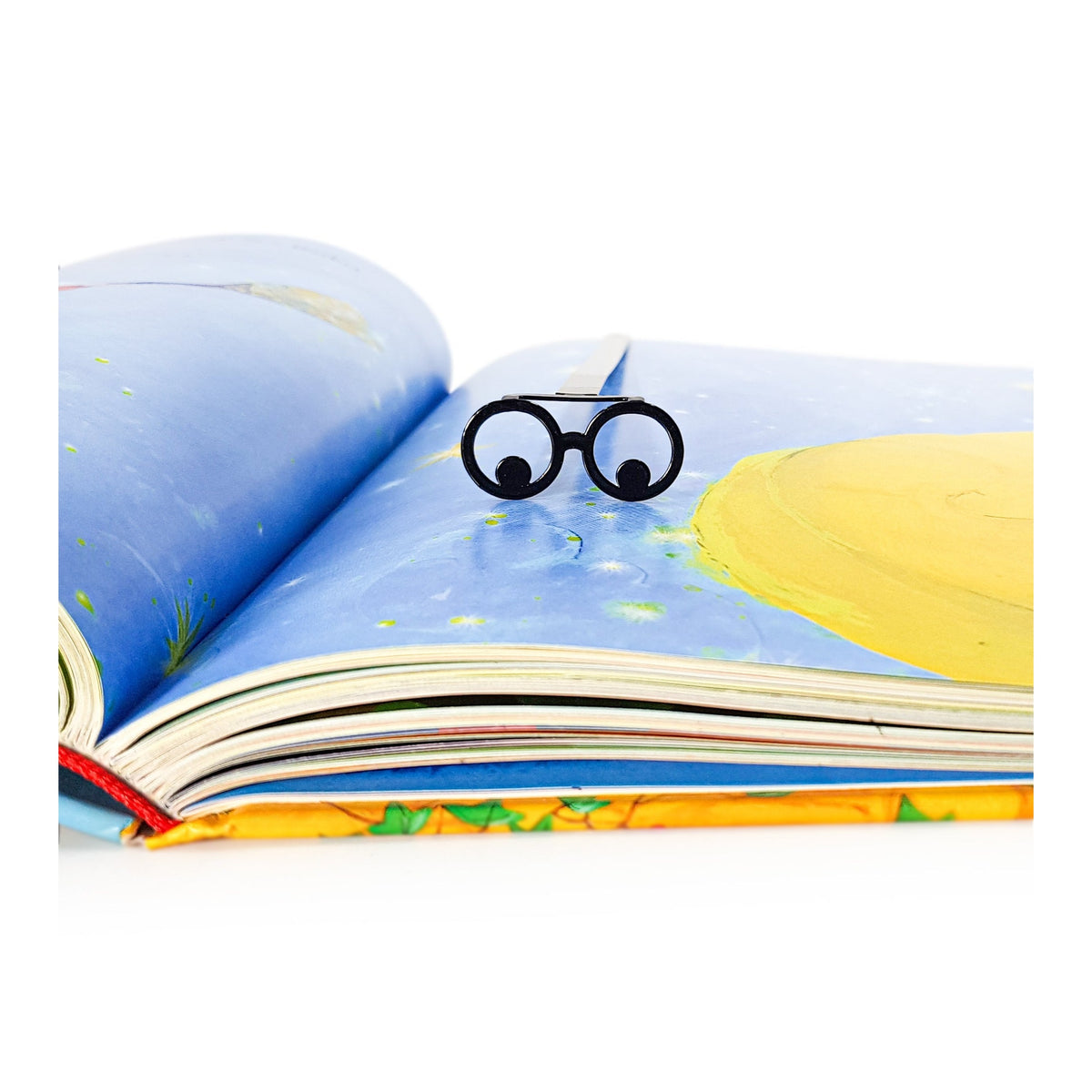 Reading Eyes metal bookmark marking a page in an illustrated book
