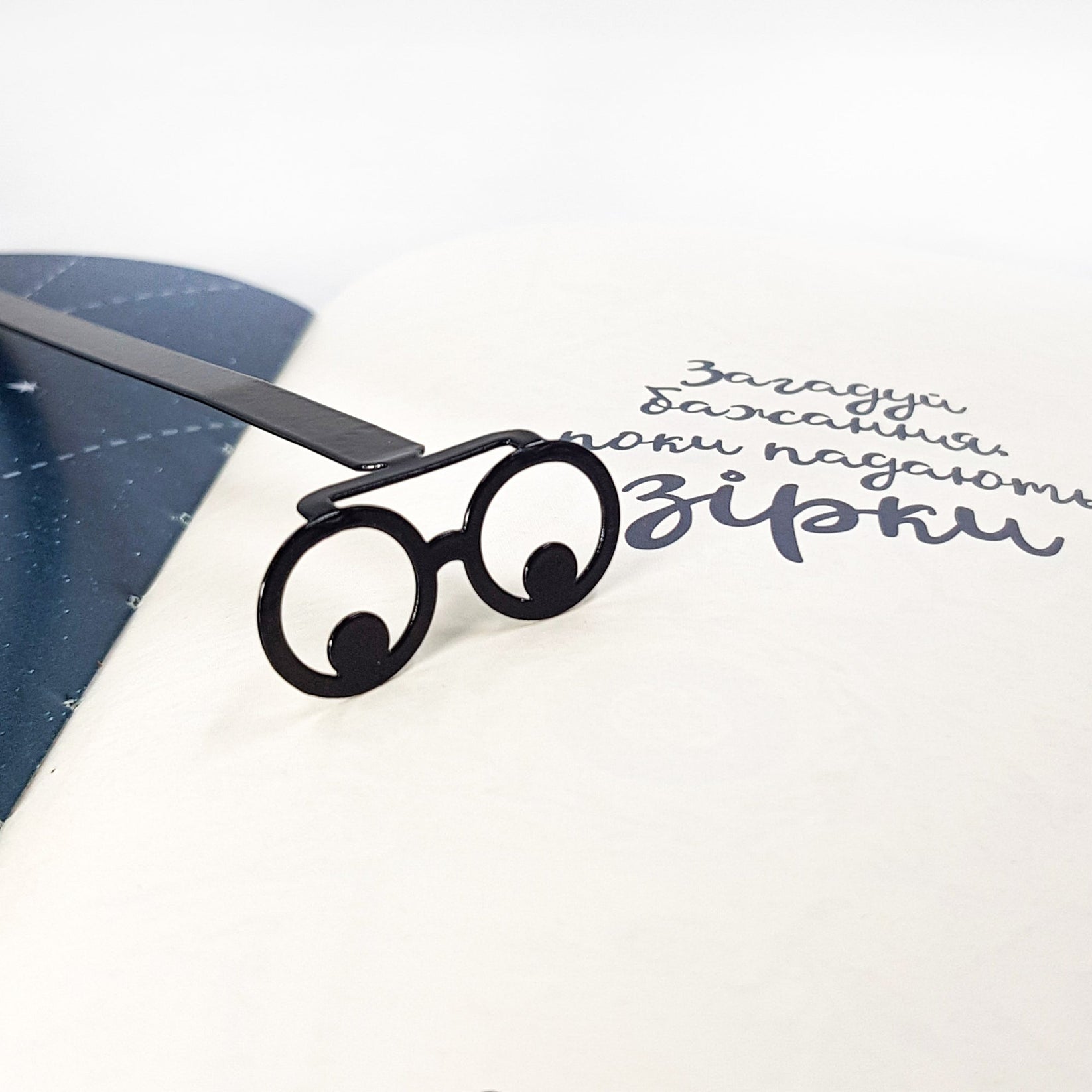 Reading Eyes metal bookmark marking a page in a notebook