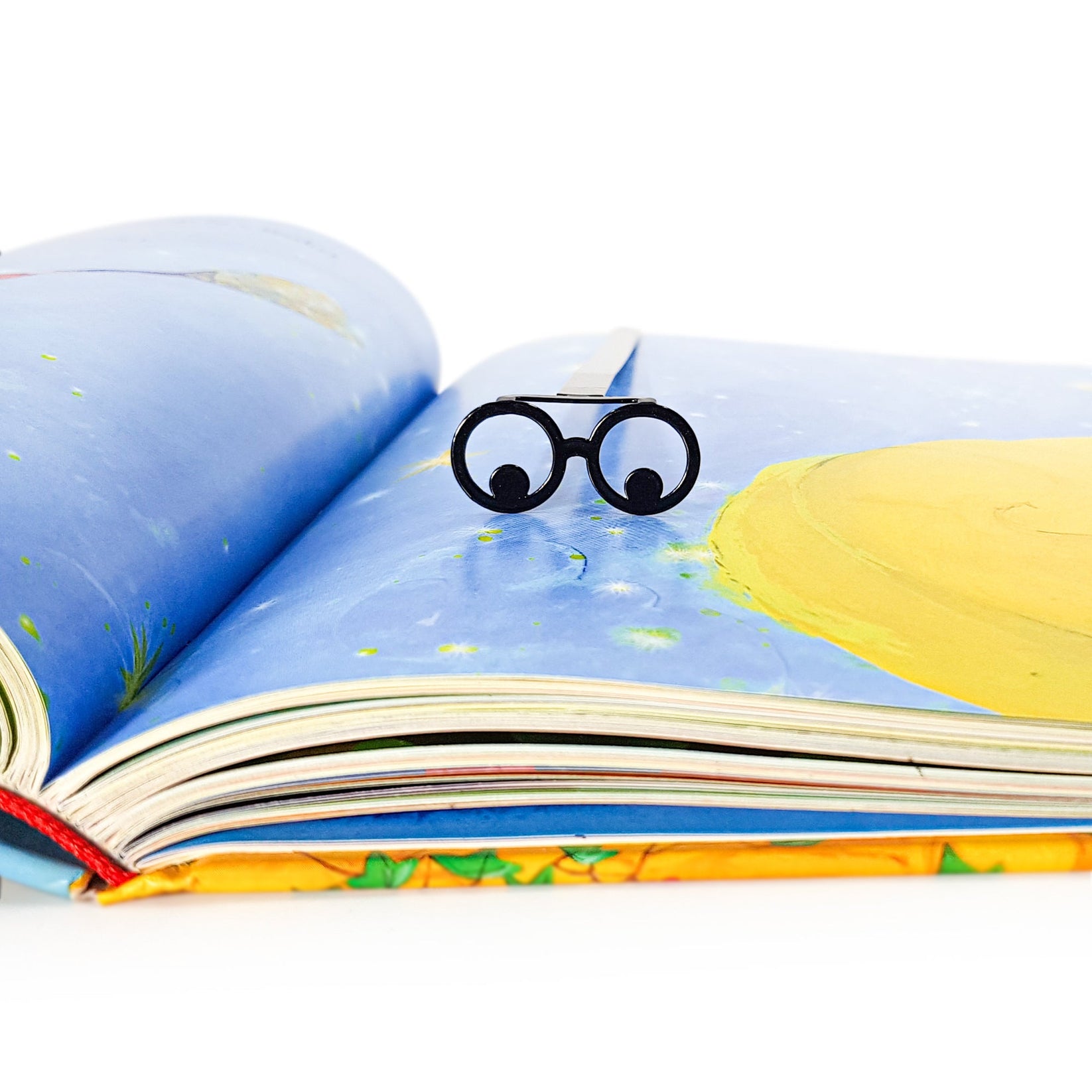 Reading Eyes metal bookmark marking a page in an illustrated book
