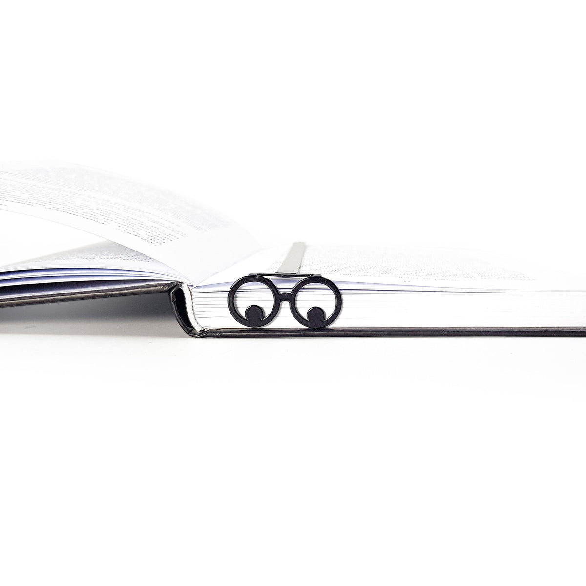 Reading Eyes metal bookmark lying across the pages of an open book