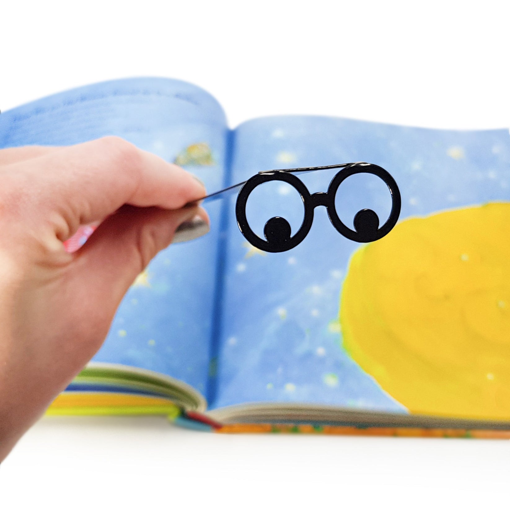 Reading Eyes metal bookmark on an illustrated page