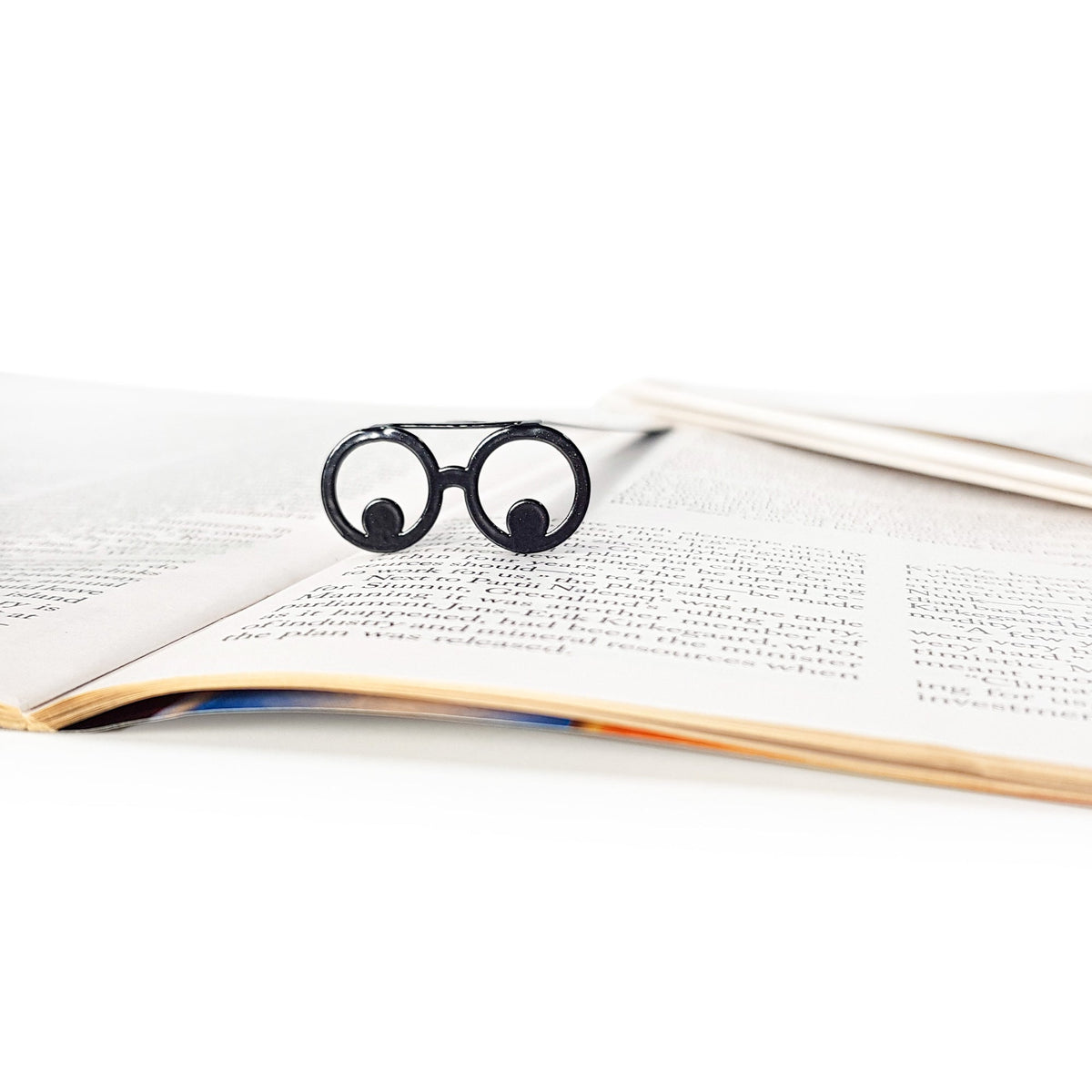 Reading Eyes metal bookmark resting on the pages of an open book