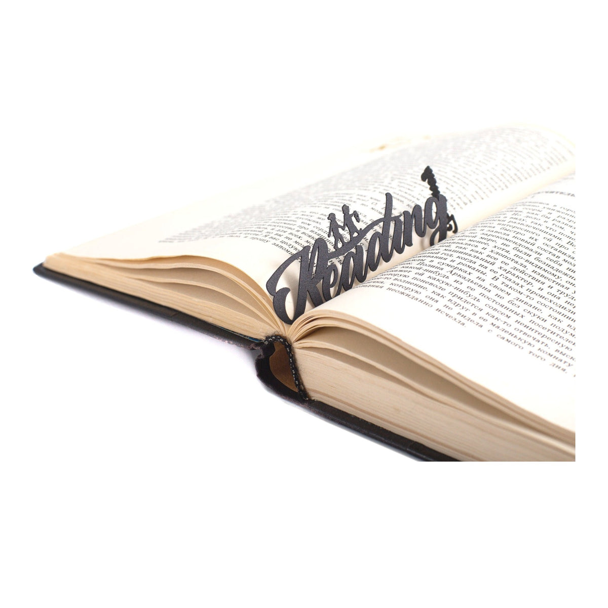 Reading Journey metal bookmark resting on the pages of an open book