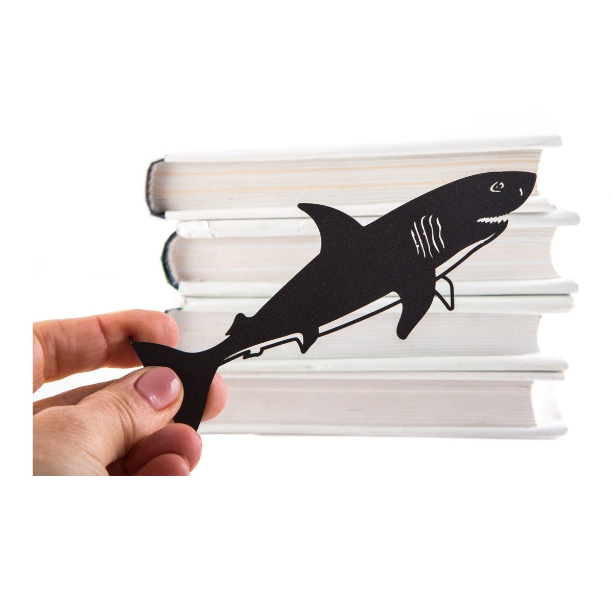 Reading Shark metal bookmark held in a hand above an open book