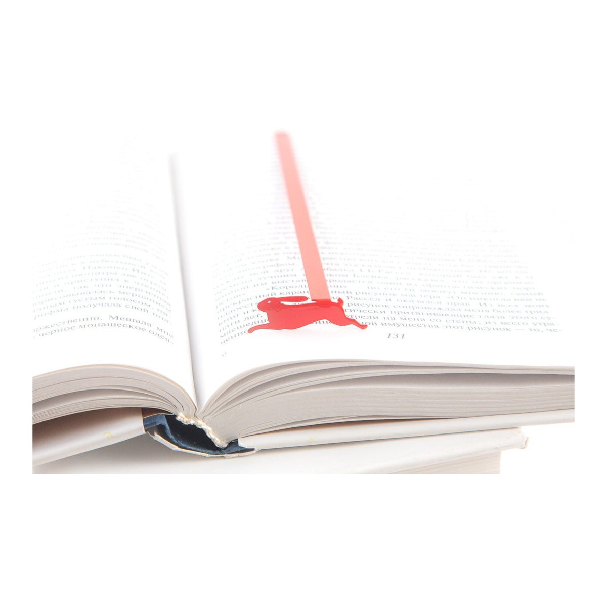 Red Rabbit metal bookmark in red resting on the pages of an open book