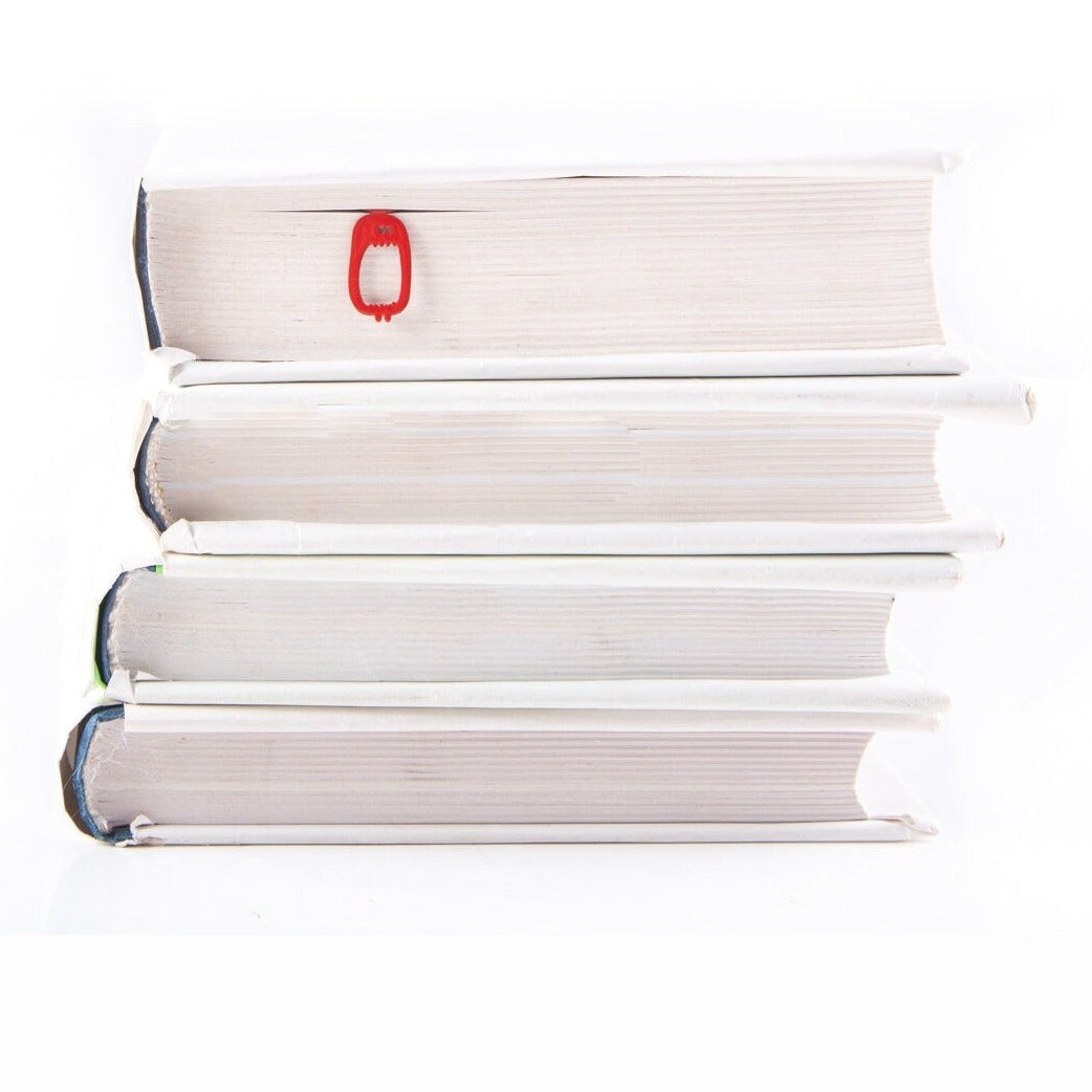 Red Screaming Monster metal bookmark in red shown with a stack of books