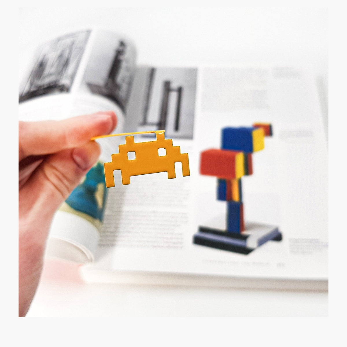 Retro Monster metal bookmark held in a hand above an open book