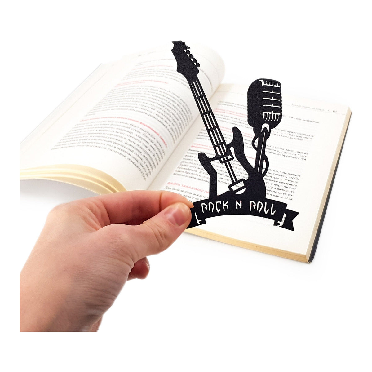 Rock and Roll metal bookmark held in a hand above an open book