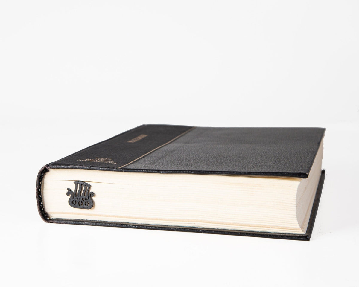 Scandinavian Vikings Ship metal bookmark in a closed book, only its top showing above the pages