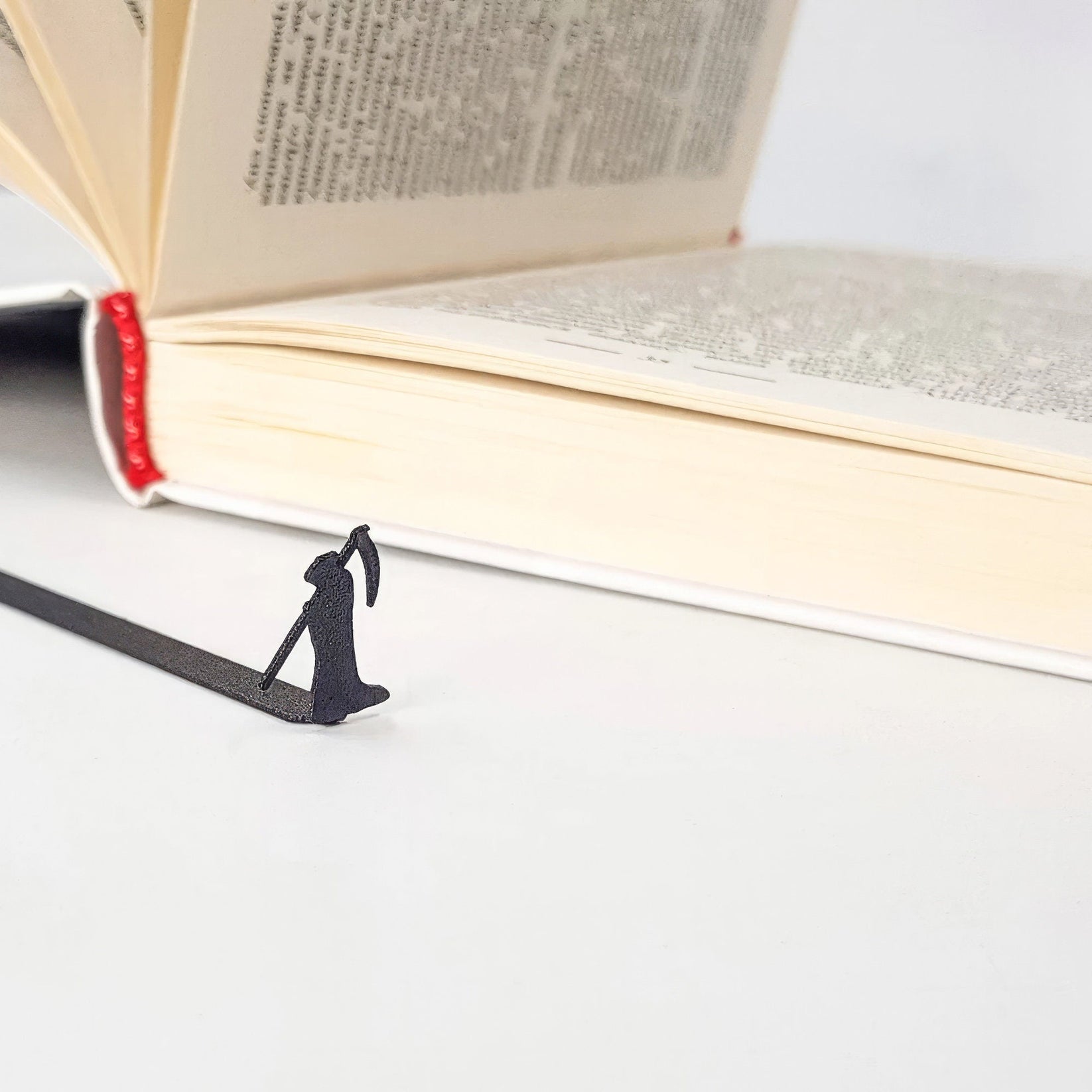 Grim Reaper metal bookmark marking a page in an open book