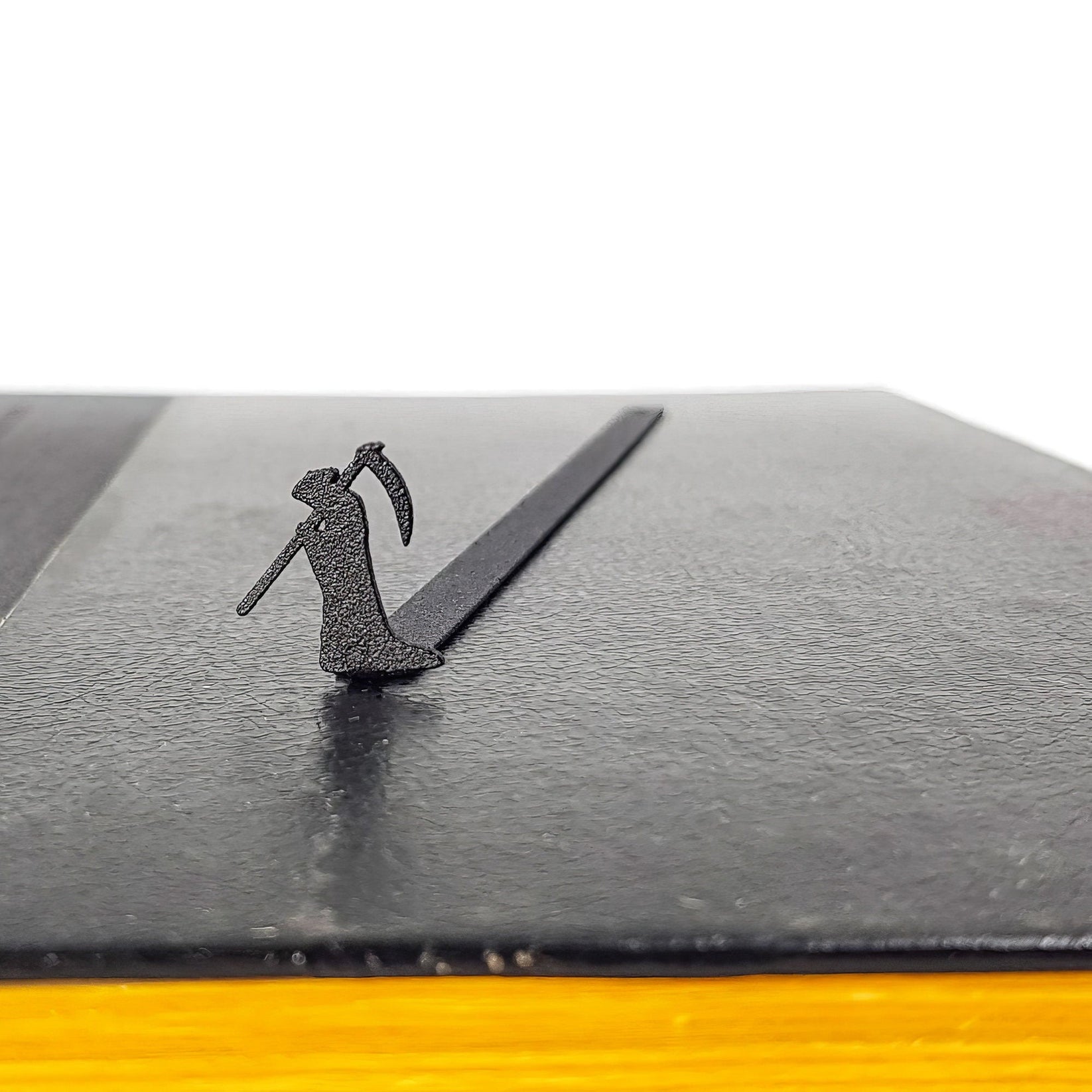 Grim Reaper metal bookmark seen from the edge of a closed book