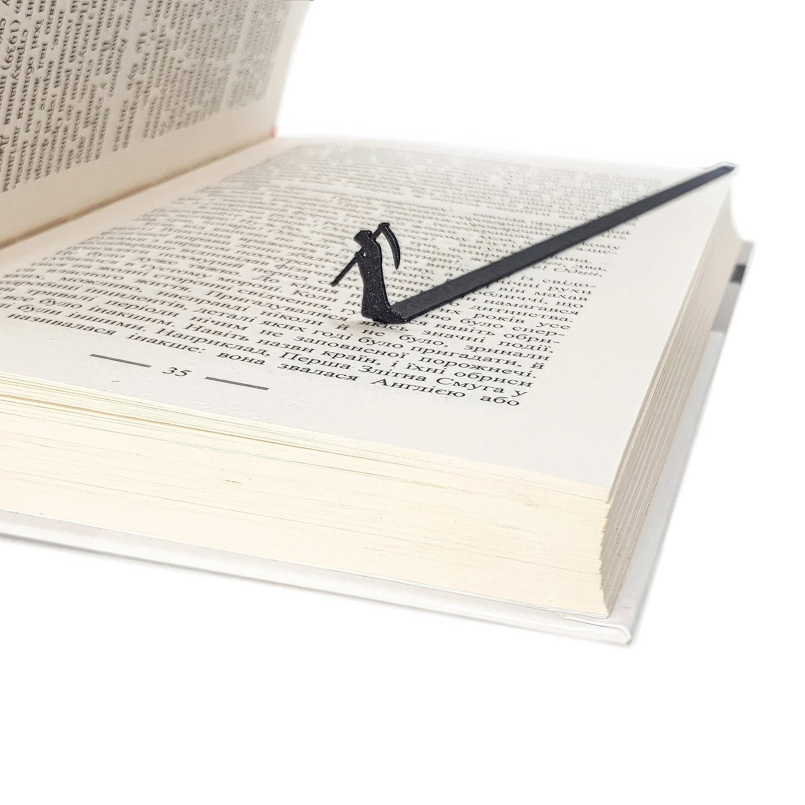 Grim Reaper metal bookmark set into the gutter of an open book