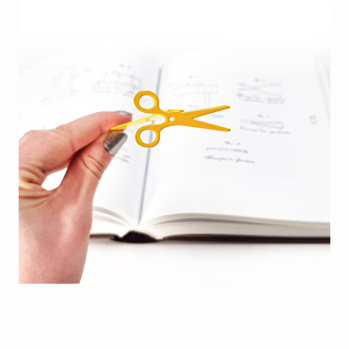 Scissors metal bookmark in gold marking a page in a notebook