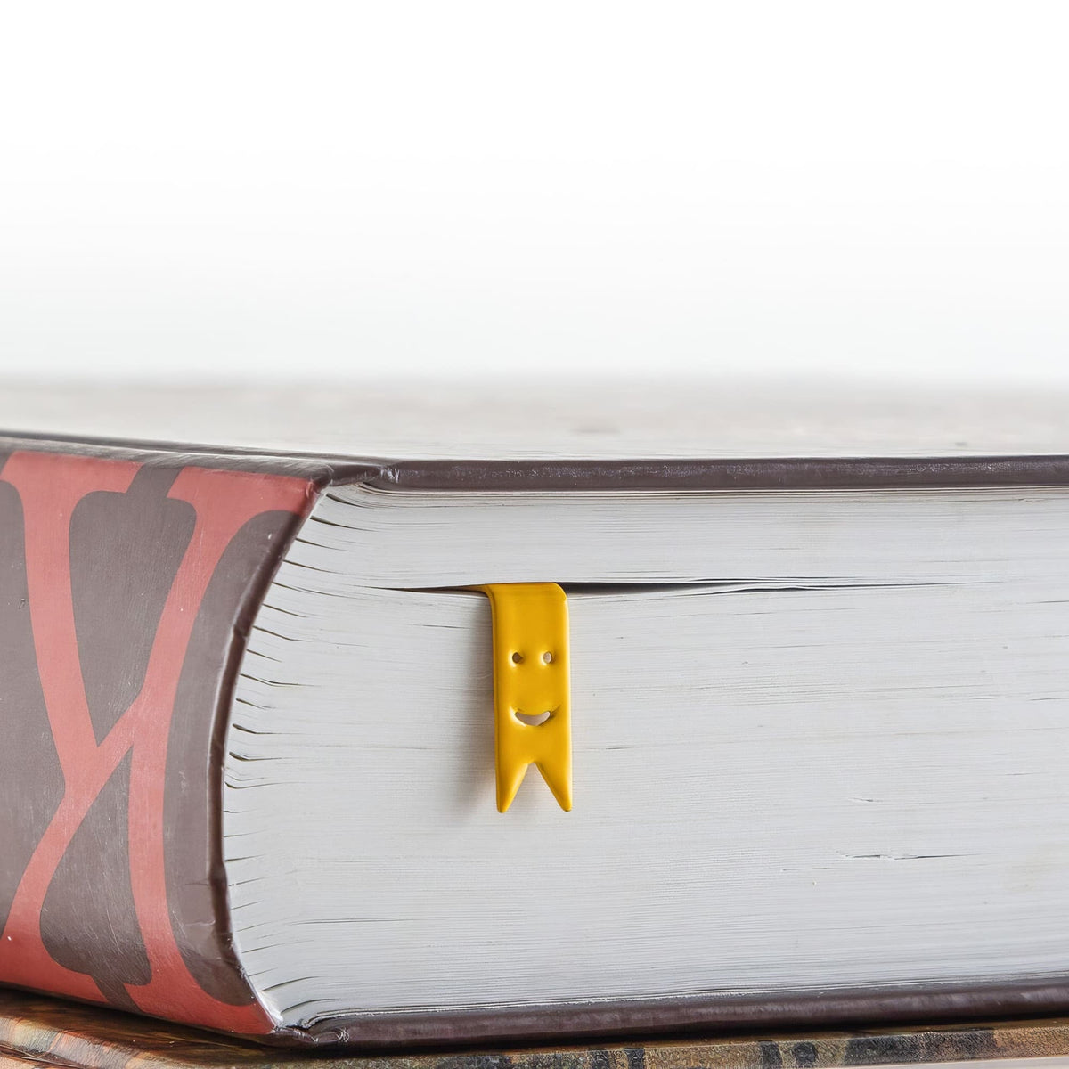 Smiling Ribbons Metal Bookmarks in a closed book, only its top showing above the pages