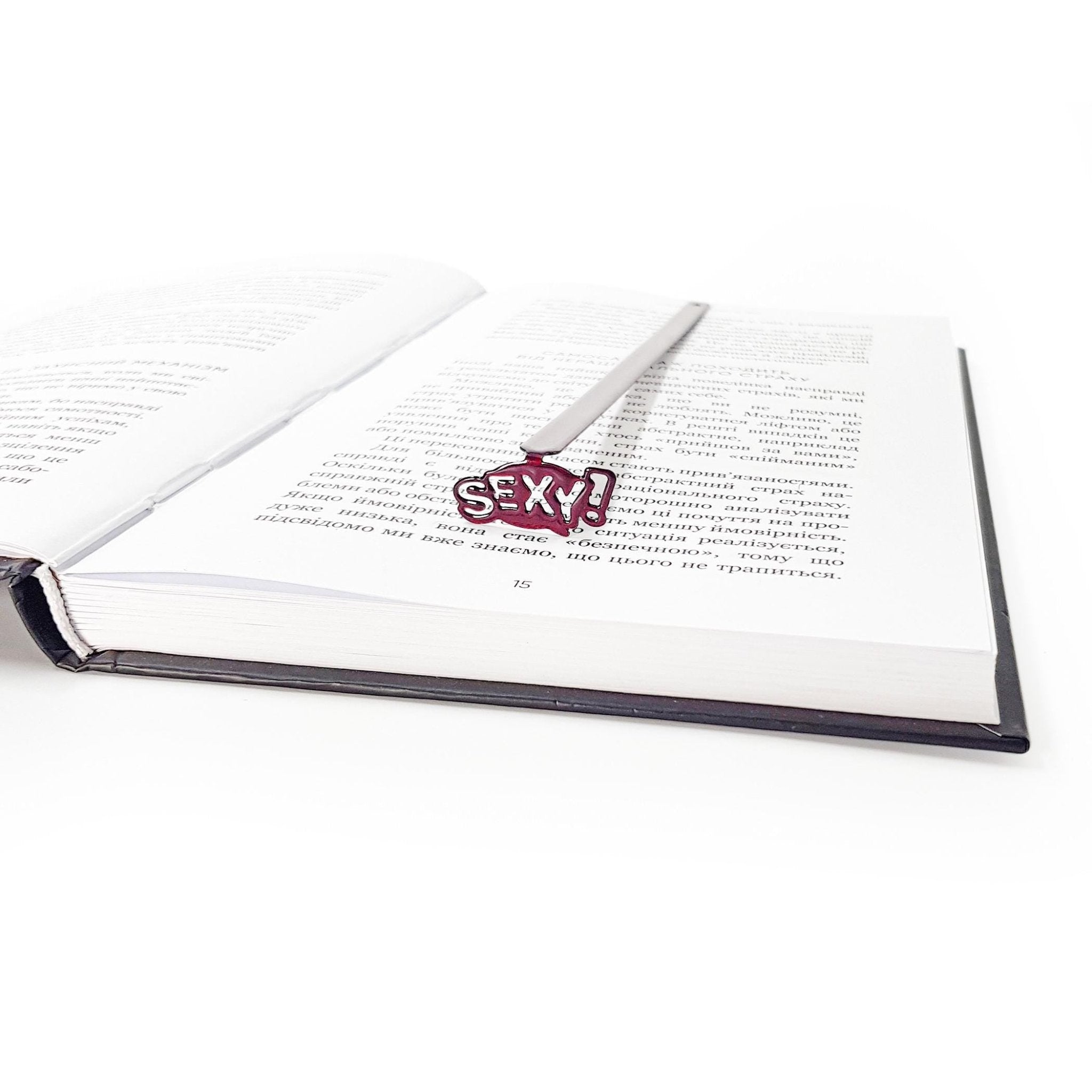 Sexy Smart metal bookmark resting between pages of an open hardcover book