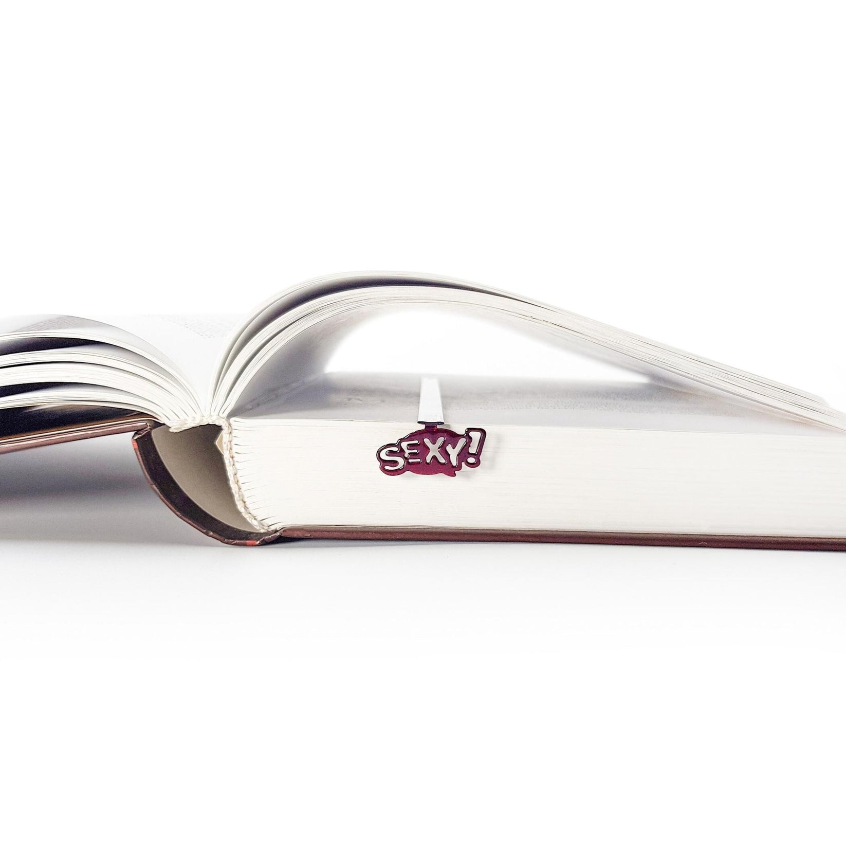 Sexy Smart metal bookmark marking a page in an open book