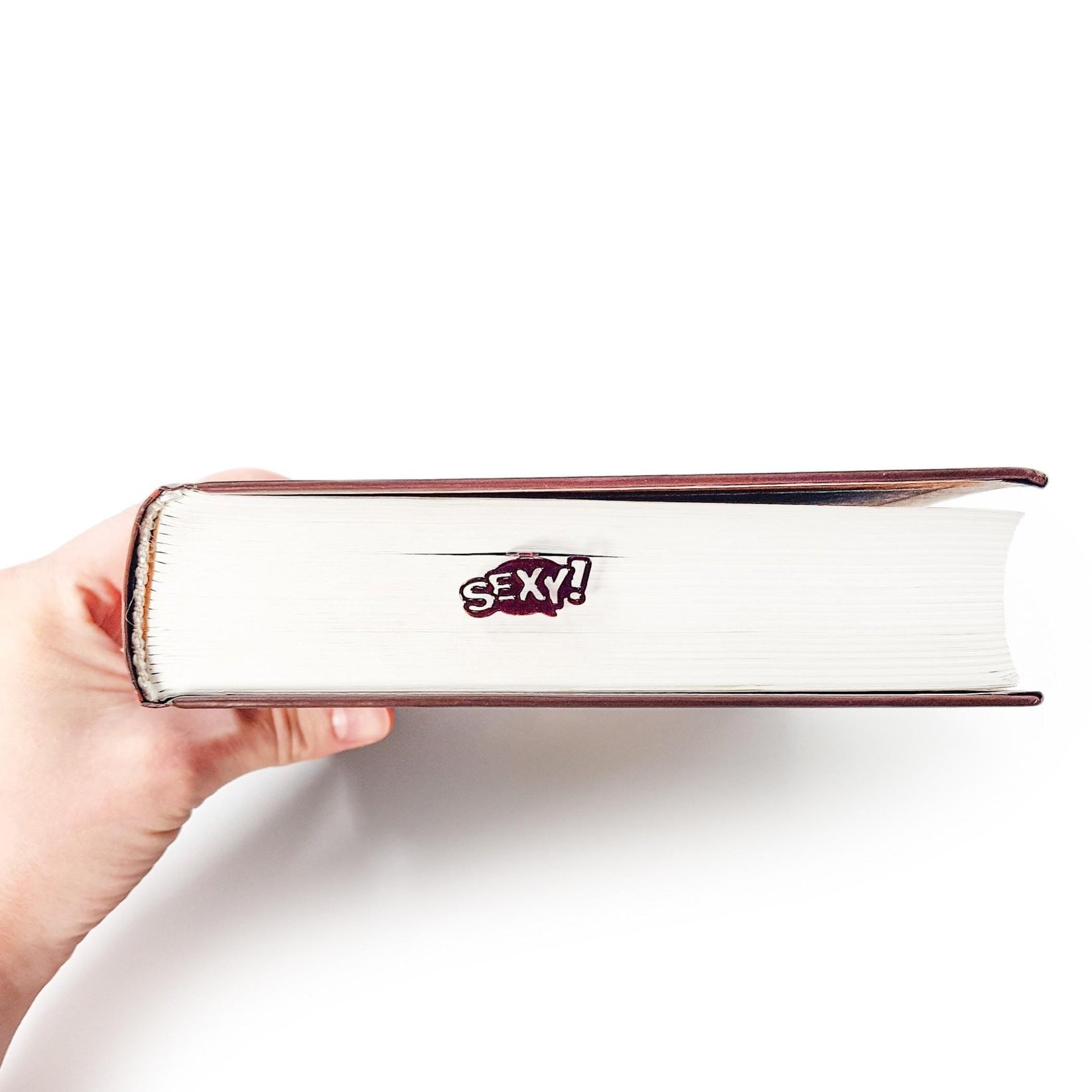 Sexy Smart metal bookmark held in a hand above an open book