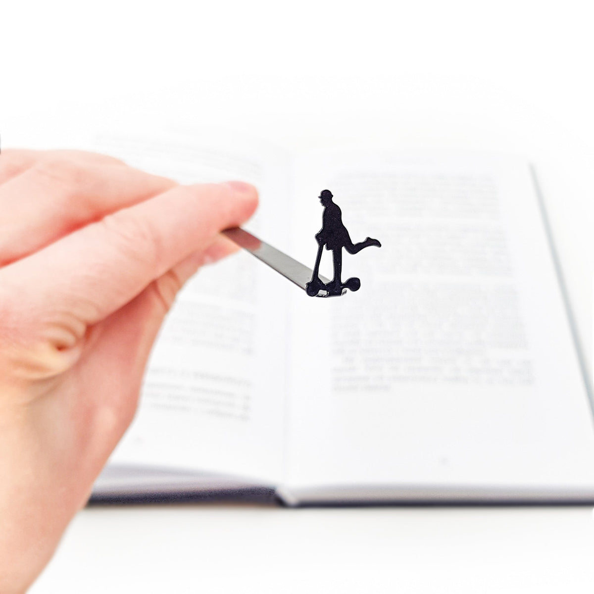 Skater Gentleman metal bookmark held in a hand above an open book