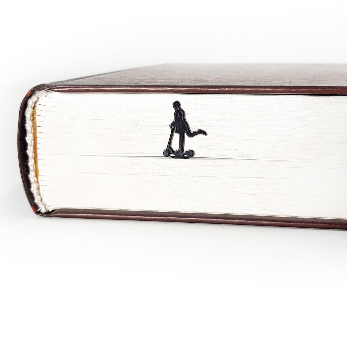 Skater Gentleman metal bookmark in a closed book, only its top showing above the pages