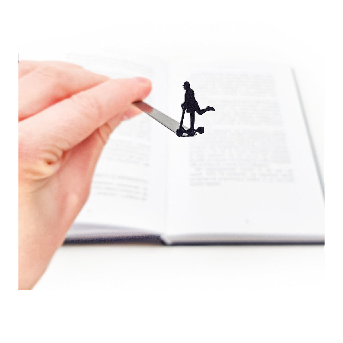 Skater Gentleman metal bookmark held in a hand above an open book