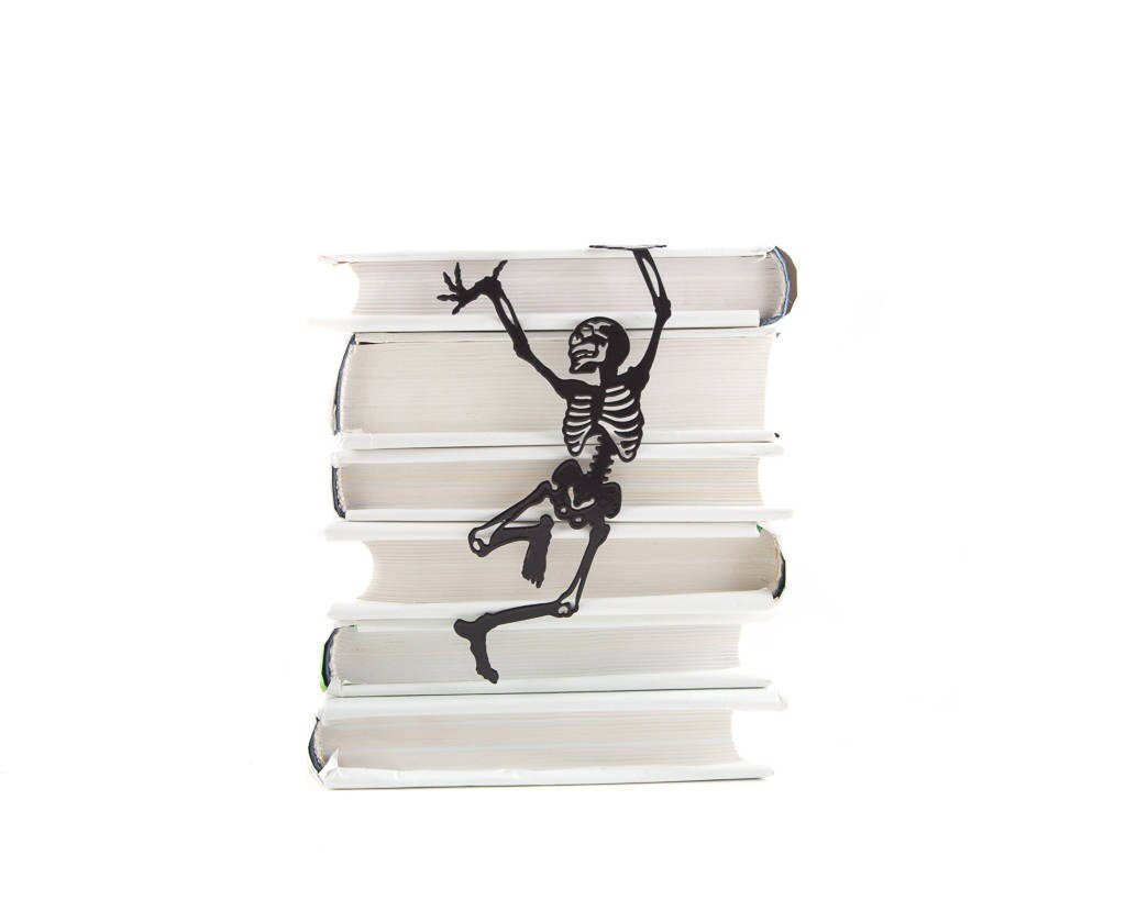Happy Skeleton metal bookmark lying on a stack of white books