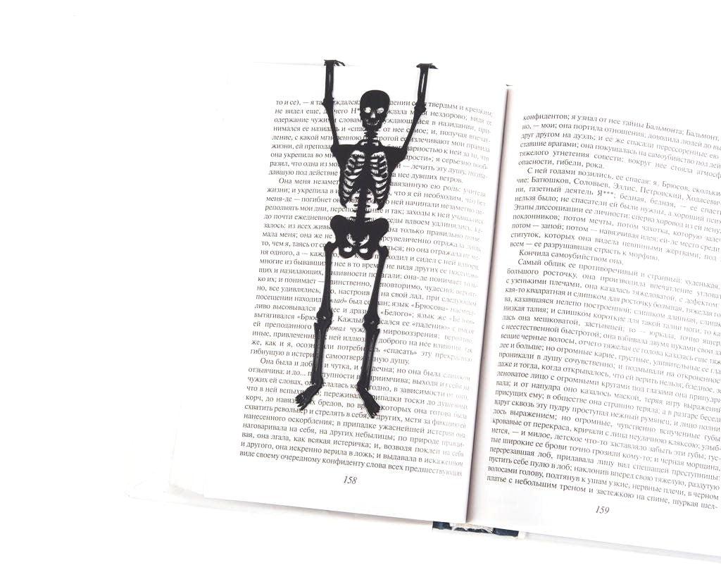 Skeleton in My Book metal bookmark resting on the pages of an open book