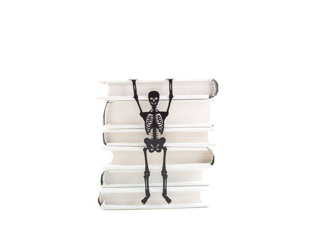 Skeleton in My Book metal bookmark lying on a stack of white books