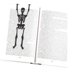 Skeleton in My Book metal bookmark resting on the pages of an open book