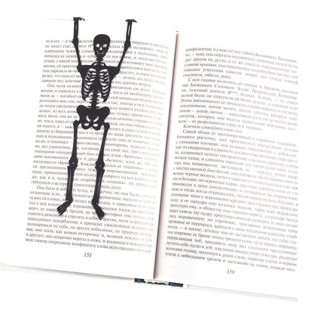 Skeleton in My Book metal bookmark resting on the pages of an open book